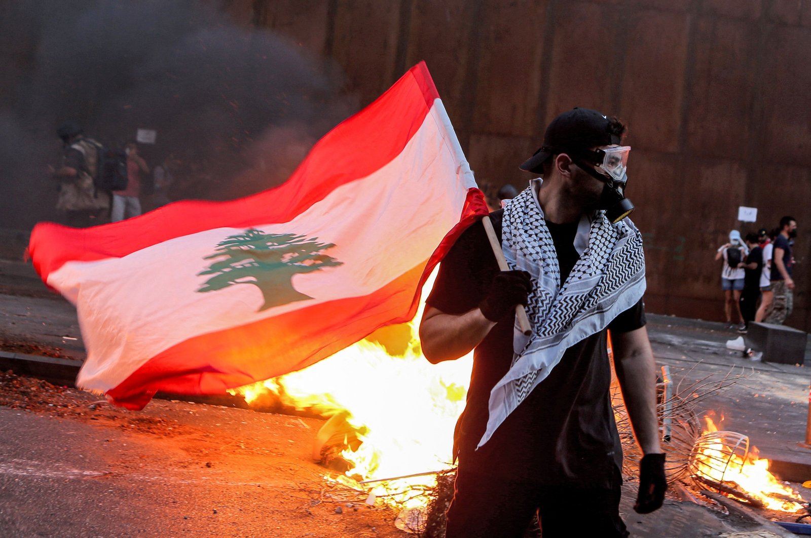 A protester stands with a Lebanese national flag during clashes with army and security forces near the Lebanese parliament headquarters in the center of the capital Beirut, Lebanon on Aug. 4, 2021. (AFP Photo)