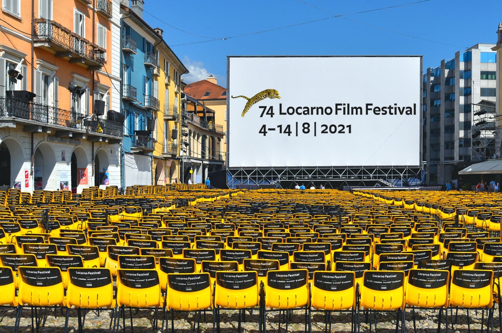The large open-air screen and yellow chairs at the Piazza Grande square with old buildings in Lorcarno for the Annual International Film Festival, Switzerland, August 15, 2019. (Shutterstock Photo) 
