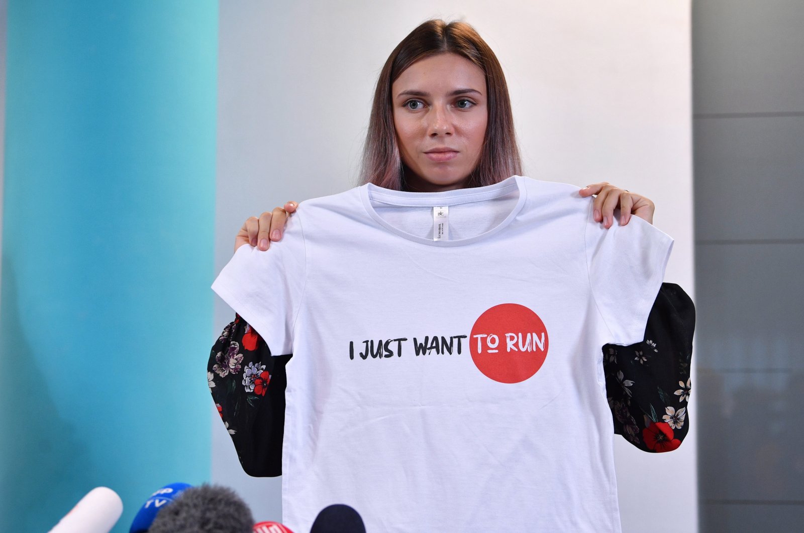 Belarusian sprinter Krystsina Tsimanouskaya, who left the Olympic Games in Tokyo and seeks asylum in Poland, holds a t-shirt at a news conference in Warsaw, Poland, Aug. 5, 2021. (Reuters Photo)