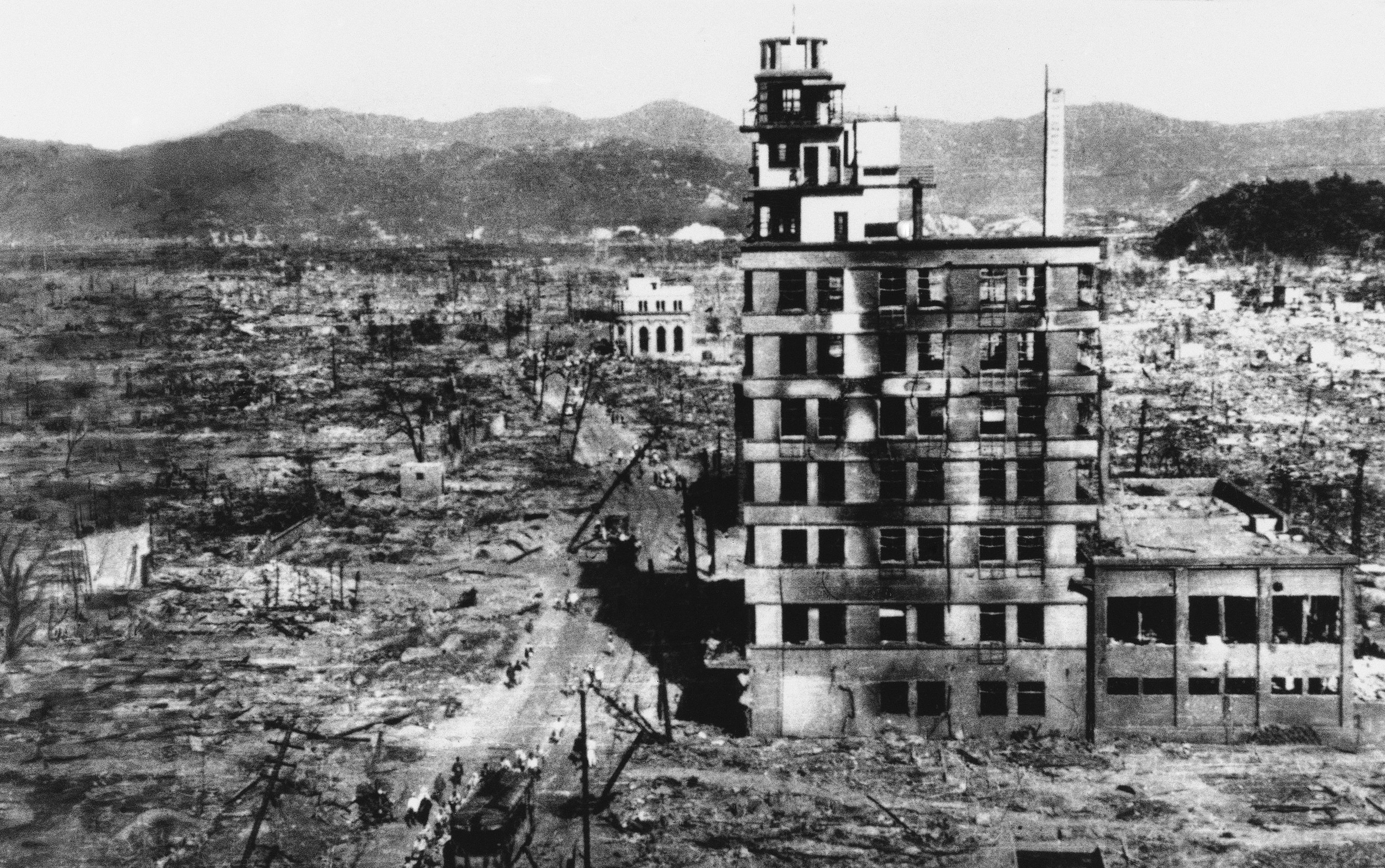 Survivors walk past one of the few buildings still standing two days after an atomic bomb was dropped on Hiroshima, Japan on August 6, 1945. (AP Photo)