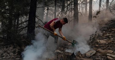 A volunteer from a nearby village uses a shovel to help contain smouldering forest fires in the hills of a recently burnt area near Kavaklıdere, a town in Muğla province, Turkey, Aug. 5, 2021. (AFP Photo)