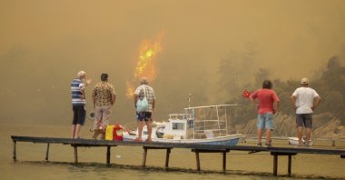 Tourists wait to be evacuated from the smoke-engulfed Mazı area as wildfires rolled down the hill toward the seashore, in Bodrum, Muğla, Turkey, Aug. 1, 2021. (AP Photo)