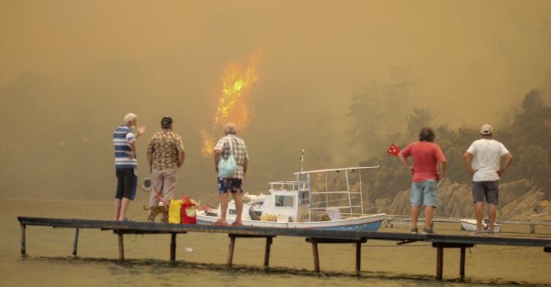 Tourists wait to be evacuated from the smoke-engulfed Mazı area as wildfires rolled down the hill toward the seashore, in Bodrum, Muğla, Turkey, Aug. 1, 2021. (AP Photo)