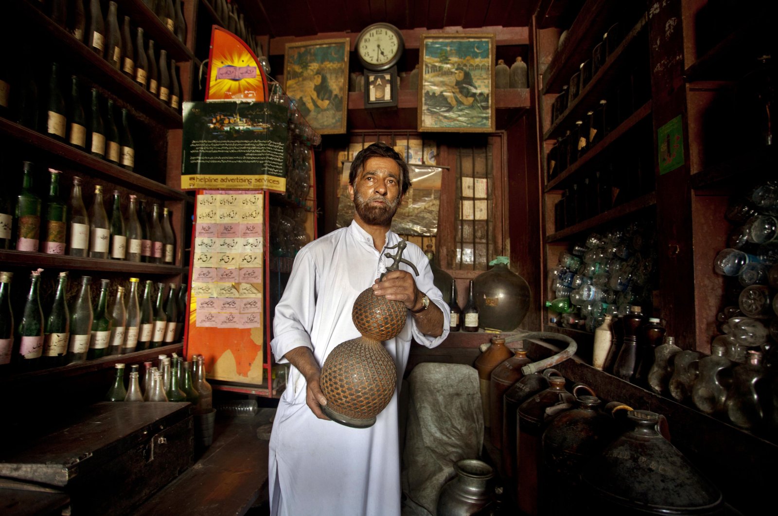 Abdul Aziz Kozgar poses for a picture as he holds a 100 to 150 year old glass jar at his shop in down town area of Srinagar, Kashmir, June 23, 2012. (AP Photo) 