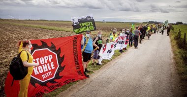 Environmental and climate activists, as well as residents of neighboring villages, form a human chain on the edge of the Garzweiler open-cast mine in Juechen, Germany, Aug. 7, 2021.  (Malte Krudewig/dpa via AP)