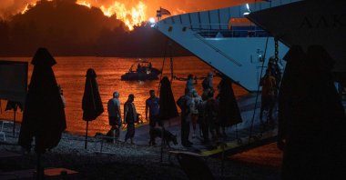 People board a ferry during evacuation as a wildfire burns in the village of Limni, on the island of Evia, Greece, Aug. 6, 2021. (Reuters Photo)