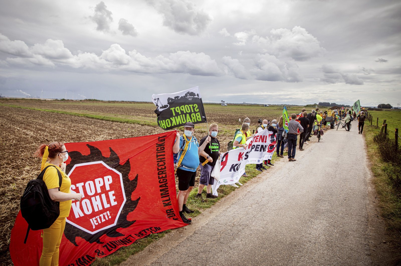 Environmental and climate activists, as well as residents of neighboring villages, form a human chain on the edge of the Garzweiler open-cast mine in Juechen, Germany, Aug. 7, 2021.  (Malte Krudewig/dpa via AP)
