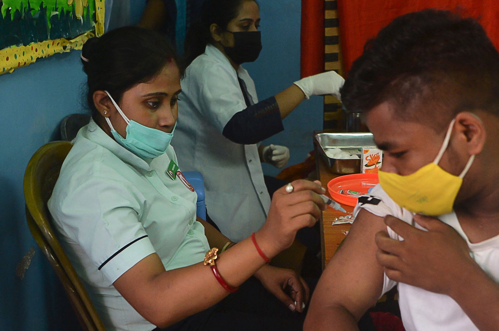 A healthcare worker inoculates a man against COVID-19 at the Bright Academy school in Siliguri, India, Aug. 7, 2021. (Photo by Diptendu DUTTA / AFP)