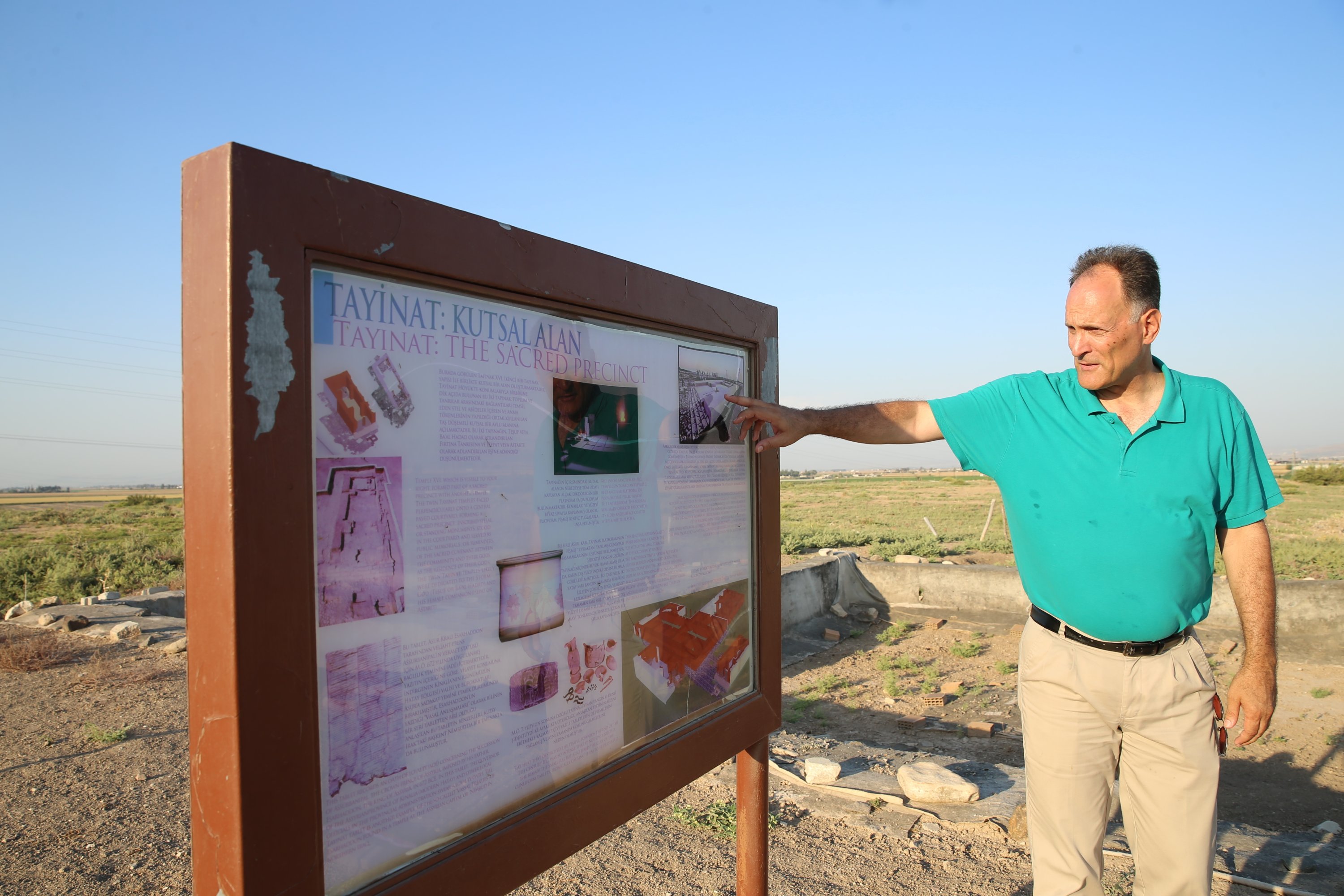 Professor Timothy Harrison shows an informative panel in Tell Tayinat, Hatay, southern Turkey, August 8, 2021. (AA Photo)