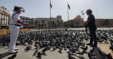 Libyan men feed pigeons in an empty Martyrs square in downtown Tripoli, Libya, Aug, 7, 2021. (AFP Photo)