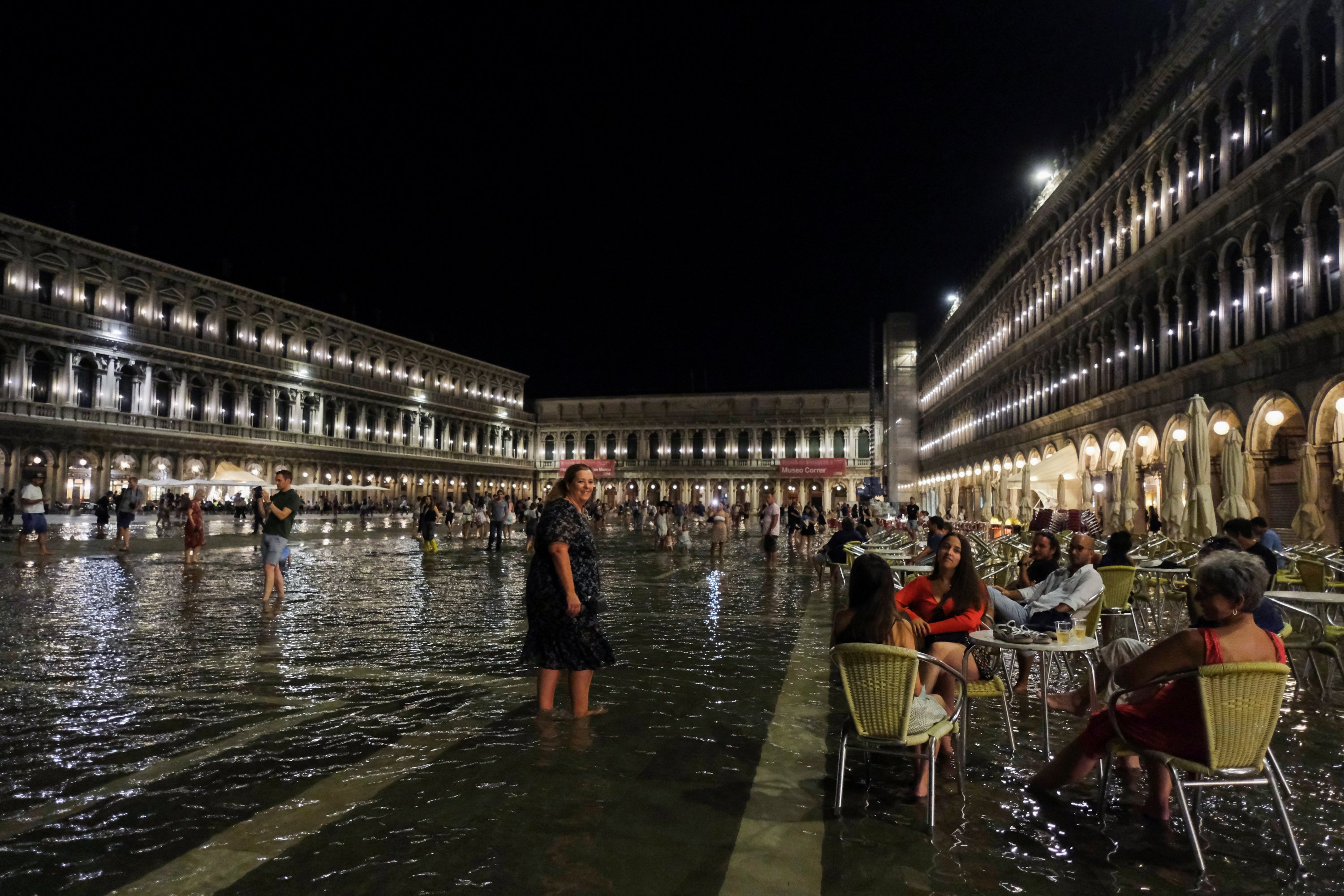 People sit at a cafe in a flooded St. Mark's Square after waters rose exceptionally high in Venice, Italy, Aug. 8, 2021. (Reuters Photo)