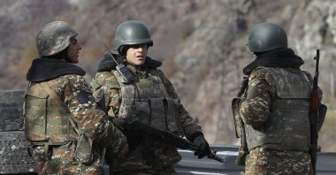 Armenian militants stand at a checkpoint near the village of Charektar in the occupied region of Nagorno-Karabakh at a new border with the Kalbajar district turned over to Azerbaijan, Nov. 25, 2020. (AP File Photo)