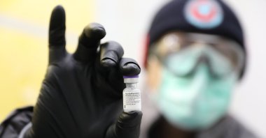 A Turkish Health Ministry official holds a vial of the Pfizer-BioNtech vaccine, in a cold storage warehouse in Istanbul, Turkey, March 29, 2021. (Turkish Health Ministry via AP)
