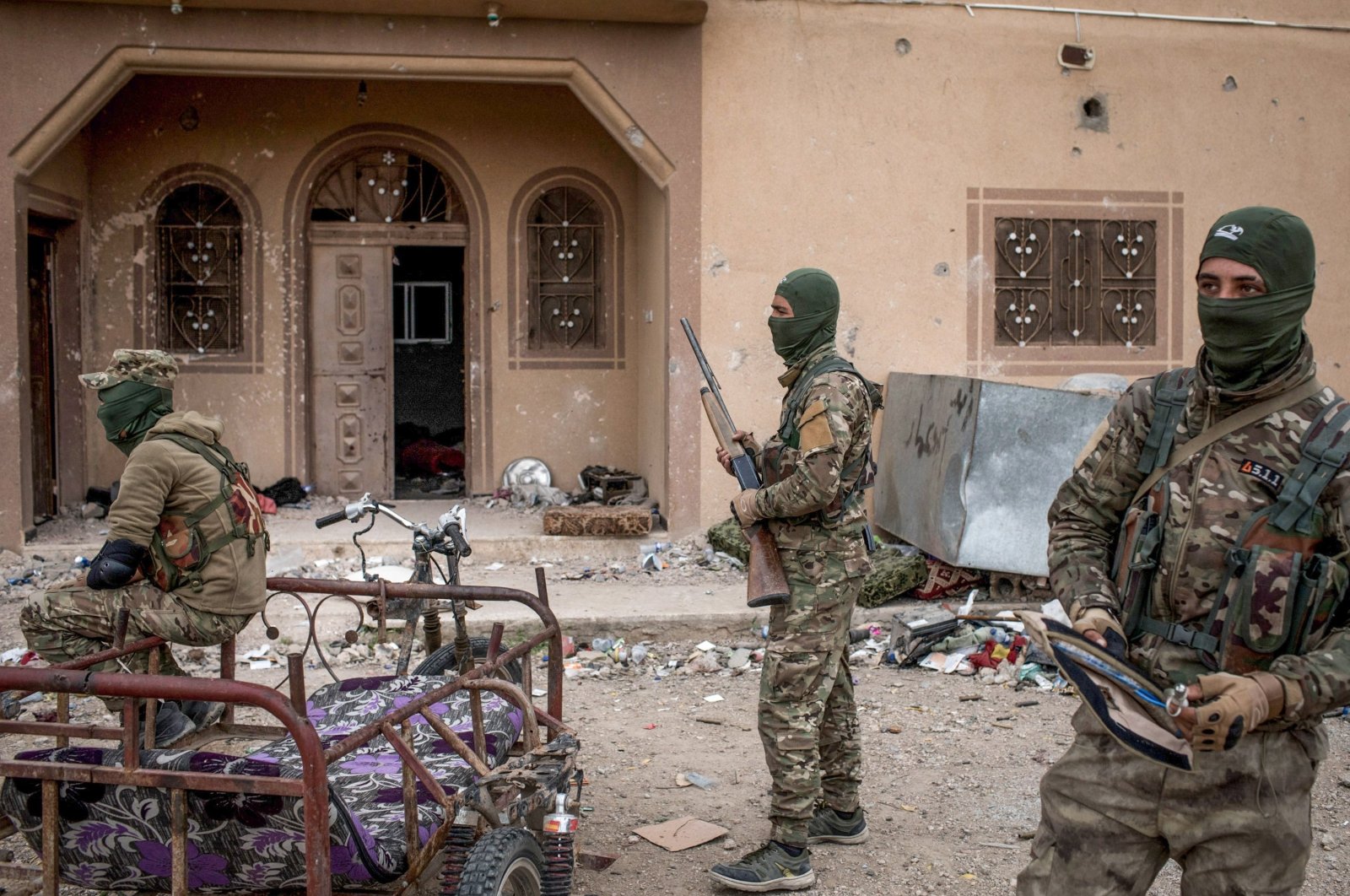 YPG/PKK terrorists are seen in front of a building in Baghouz, Syria, on March 24, 2019. (Photo by Chris McGrath/Getty Images)
