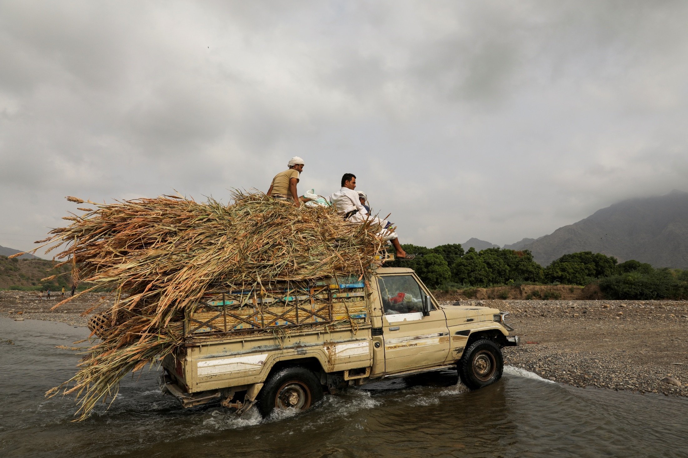 Villagers ride on top a vehicle loaded with fodder as they cross a spring lake in Khamis Banisaad district of al-Mahweet province, Yemen, June 23, 2021. (Reuters Photo)