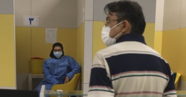 A health worker, left, waits to vaccinate people against COVID-19 as a man waits his turn at a vaccination center in Iran Mall in Tehran, Iran, Aug. 9, 2021. (AP Photo)