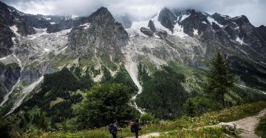 Hikers walk on a path near the Planpicieux (C) and Grand Jorasses Glaciers (R) in Courmayeur, Alps Region, north-western Italy, Aug. 3, 2021. (AFP Photo)