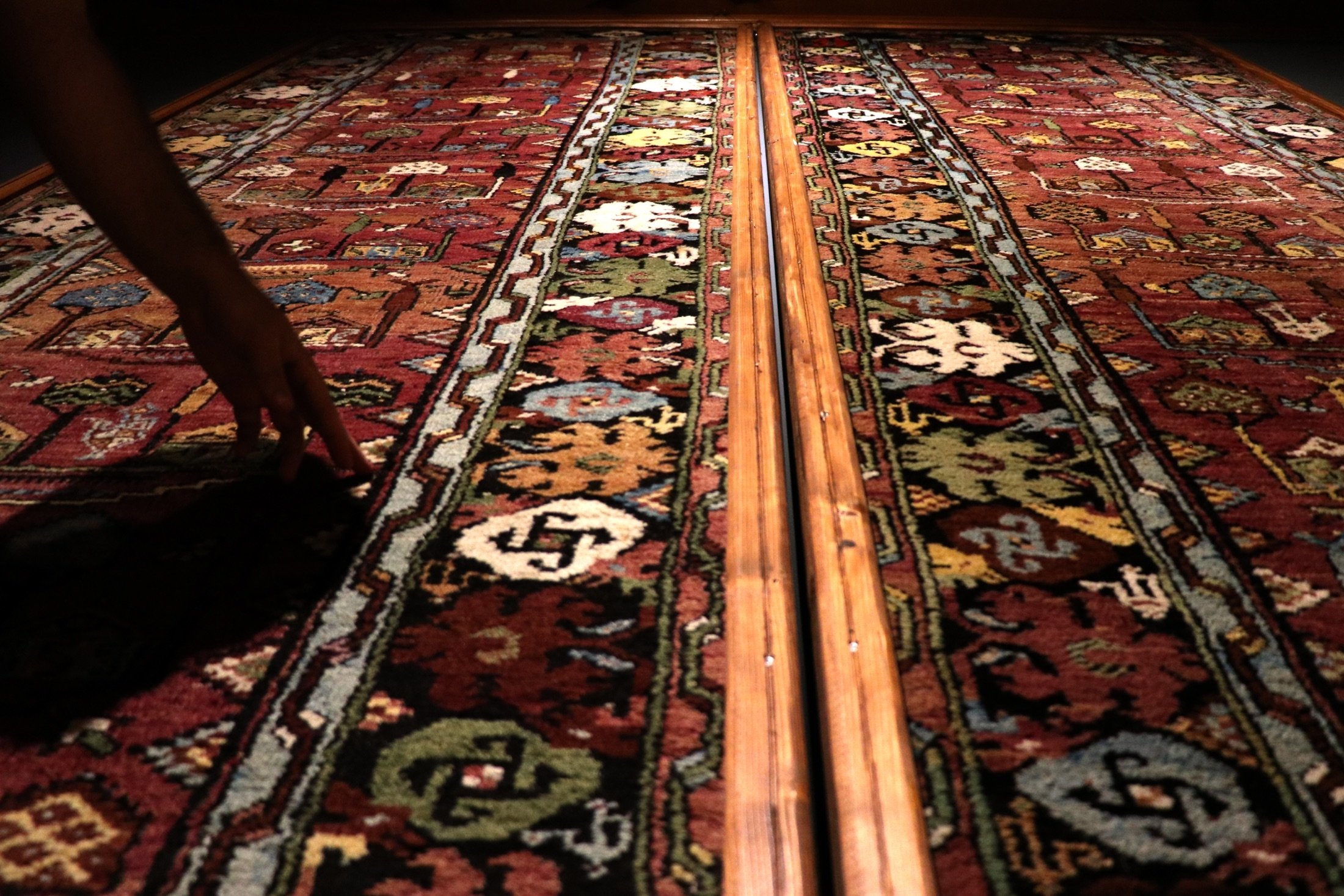 A person touches a historical 100-year-old carpet as it is displayed in the Sille Museum in the Sille district of Konya, Turkey, Aug. 11, 2021. (AA Photo)