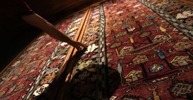 A person touches a historical 100-year-old carpet as it is displayed in the Sille Museum in the Sille district of Konya, Turkey, Aug. 11, 2021. (AA Photo)