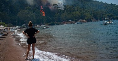 A woman watches the forest burning from a beach in Muğla, Turkey, on Aug. 3, 2021. (AFP Photo)