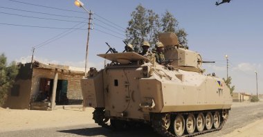 Egyptian Army soldiers patrol in an armored vehicle backed by a helicopter gunship during a sweep through villages in Sheikh Zuweyid, north Sinai, Egypt, May 12, 2013. (AP Photo)