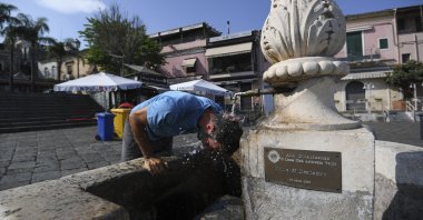 A man refreshes himself at a fountain in Aci Trezza, near Catania, Sicily, Italy, Aug. 13, 2021. (AP Photo)