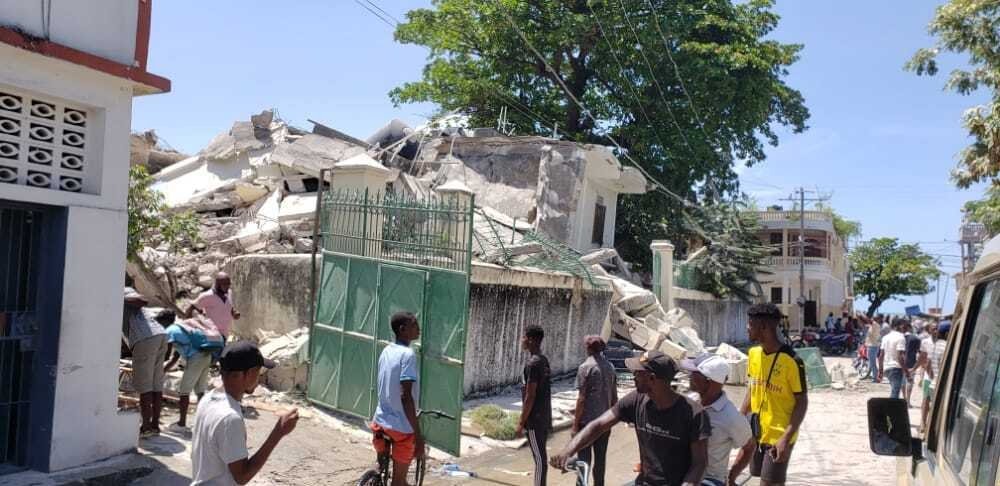 People stand outside the residence of the Catholic bishop after it was damaged by an earthquake in Les Cayes, Haiti, Saturday, Aug. 14, 2021. (AP Photo)