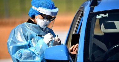 A health worker takes a swab sample at a COVID-19 drive through testing site in the Smithfield suburb of Sydney, Australia, Aug. 12, 2021. (AFP Photo)