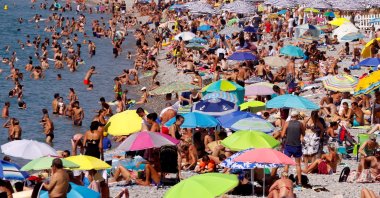 People enjoy a warm and sunny day on the beach of the Promenade des Anglais in Nice, Aug. 14, 2021. (Reuters Photo)