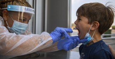 A health worker collects a swab sample from a kid to test for COVID-19 at a testing center, in Tel Aviv, Israel, Aug. 9, 2021. (AP Photo)