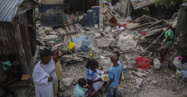 A family eats breakfast in front of homes destroyed by a 7.2 magnitude earthquake in Les Cayes, Haiti, Sunday, Aug. 15, 2021. (AP Photo)