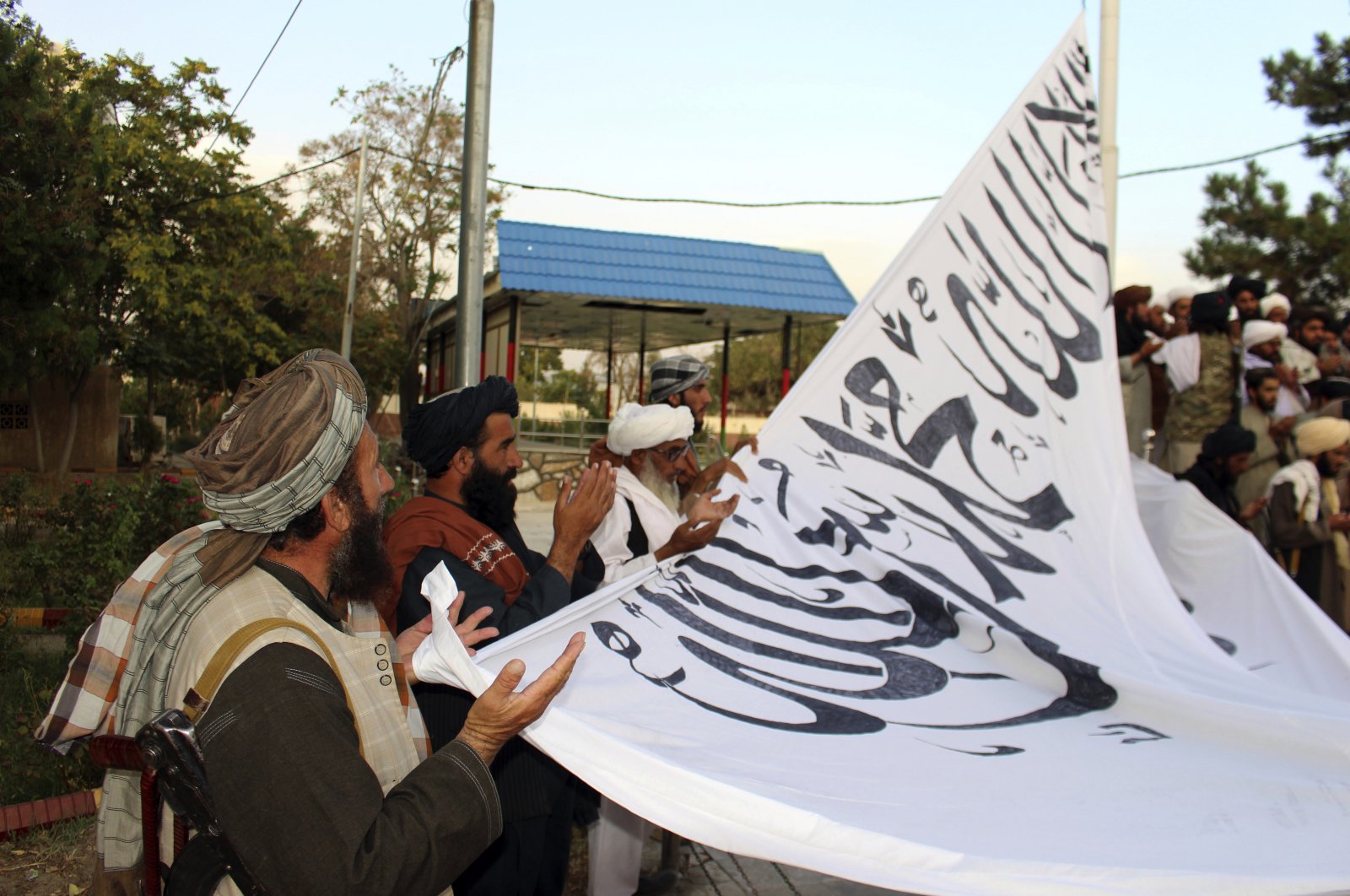 Taliban fighters pray while raising their flag at the Ghazni provincial governor's house, in Ghazni, southeastern Afghanistan, Sunday, Aug. 15, 2021. (AP Photo)
