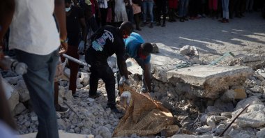 People cover the body of a person lying on the debris with a sheet, after a 7.2 magnitude earthquake, in Les Cayes, Haiti, Aug. 15, 2021. (Reuters Photo)