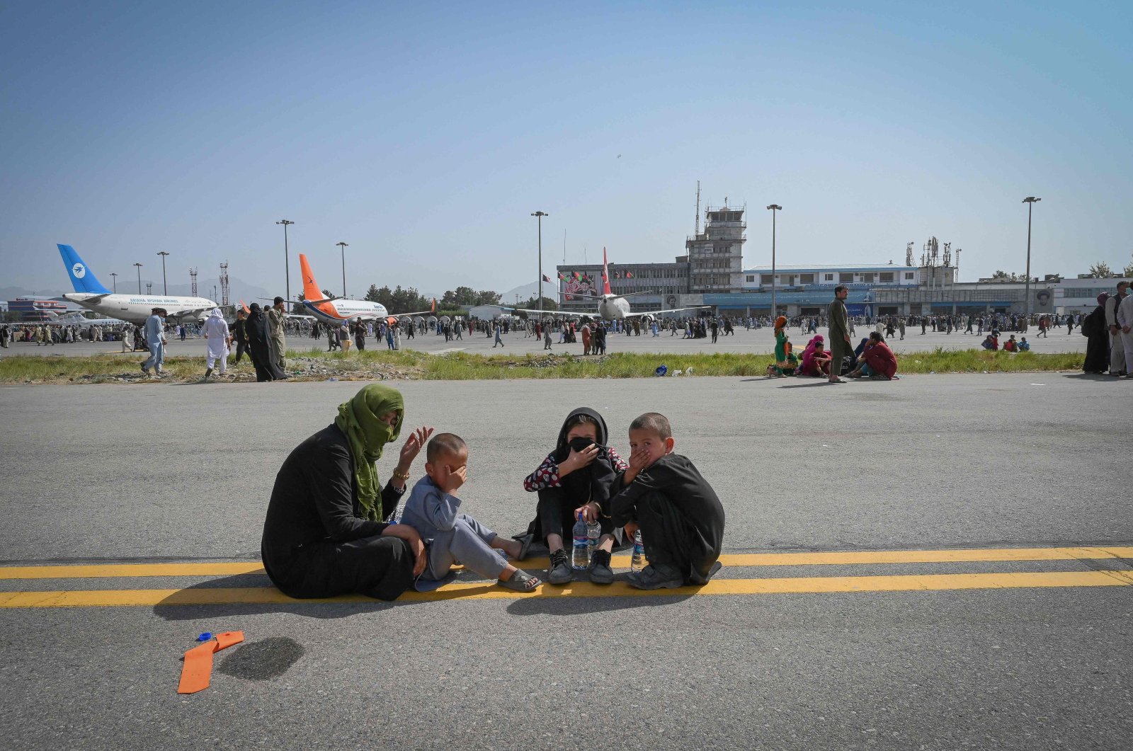 Afghan people sit along the tarmac as they wait to leave the Kabul Hamid Karzai International Airport in Kabul, Afghanistan on Aug. 16, 2021. (AFP Photo)