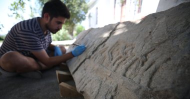 An archaeologist works on an ancient stone relief found in the ancient city of Daskyleion, Balıkesir, western Turkey, Aug. 16, 2021. (AA Photo)