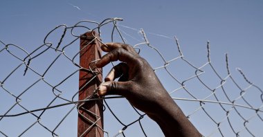 The hand and arm of a refugee on the perimeter fence of Tillaberi Refugee settlement located some 50 miles (80 kilometers) from Niger's capital of Niamey, Dec. 13, 2019. (Getty Images Photo)