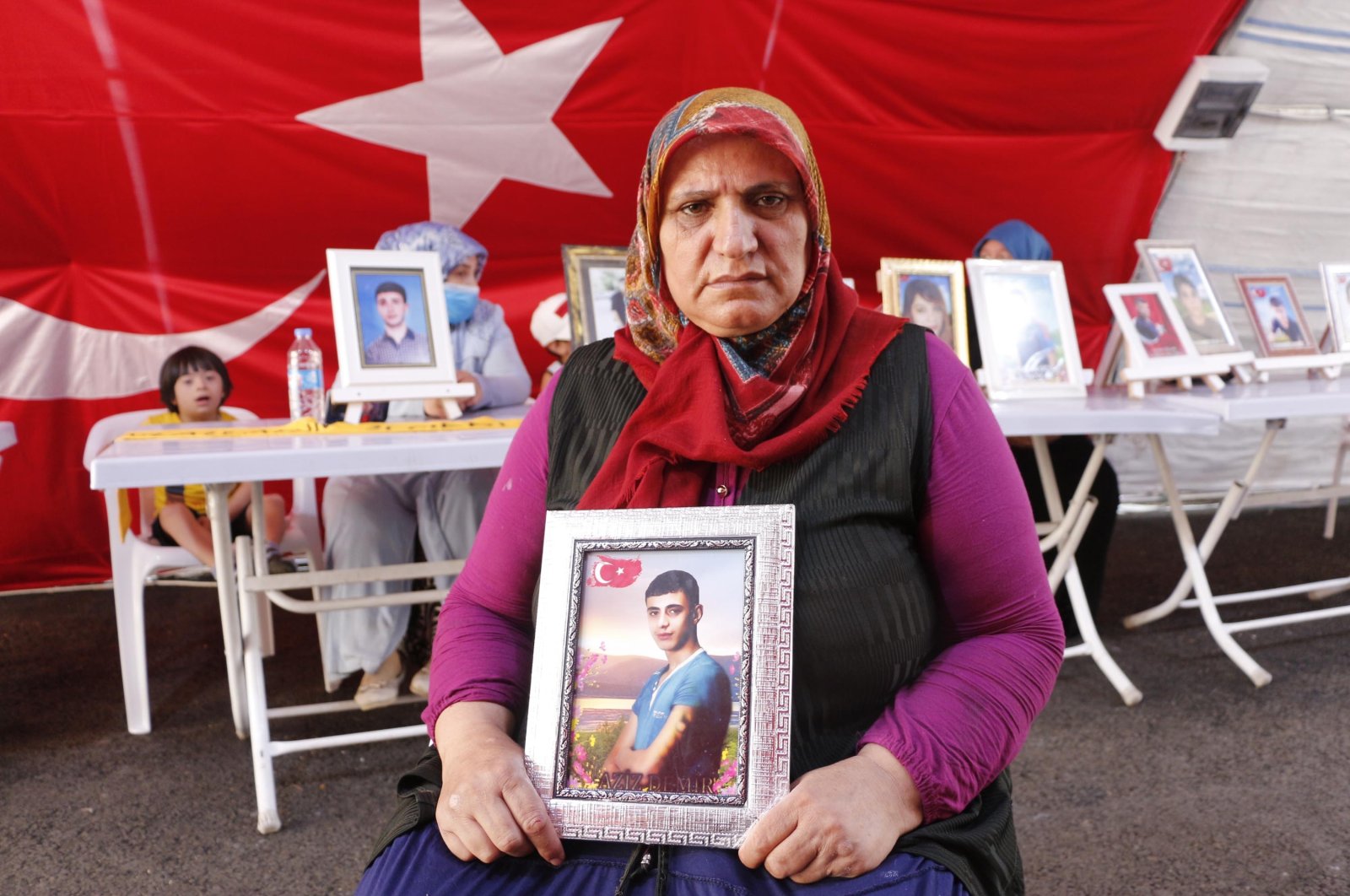 Güzide Demir holds a photo of her son, Aziz, in front of the HDP headquarters in southeastern Turkey, Aug. 5, 2021. (DHA File Photo)