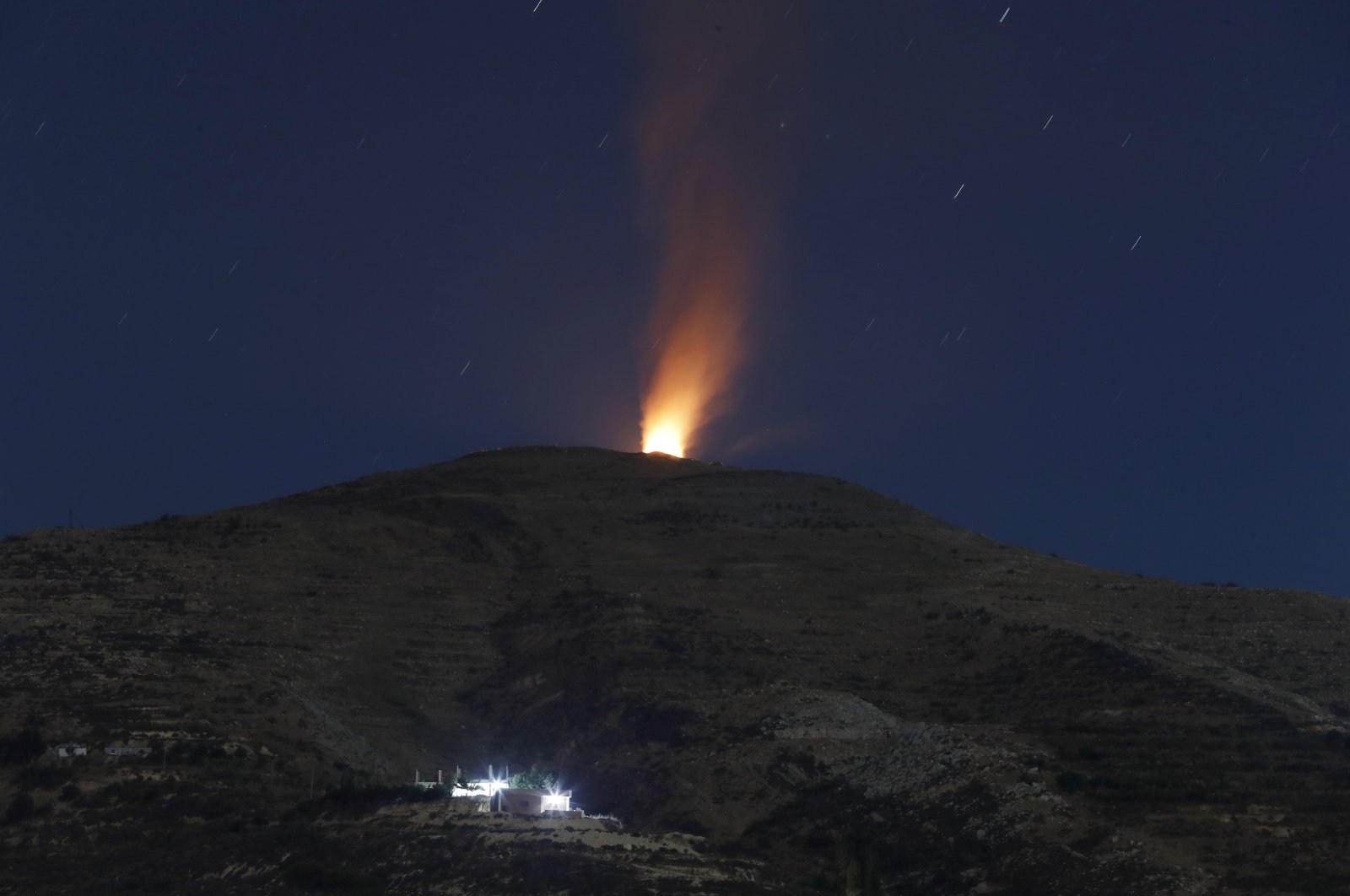 A long exposure picture taken from the Druze village of Majdal Shams in the annexed Golan Heights shows flames rising from the Syrian side of the border after an alleged strike, Aug. 17, 2021. (EPA Photo)