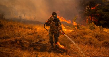 A volunteer uses a water hose to extinguish a fire in the village of Markati, near Athens, Greece, on Aug. 16, 2021. (AFP Photo)