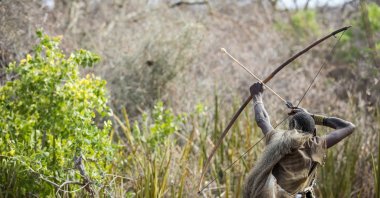 A Hadza hunter draws his bow as he prepares to shoot an arrow in northern Tanzania. (Shutterstock Photo)
