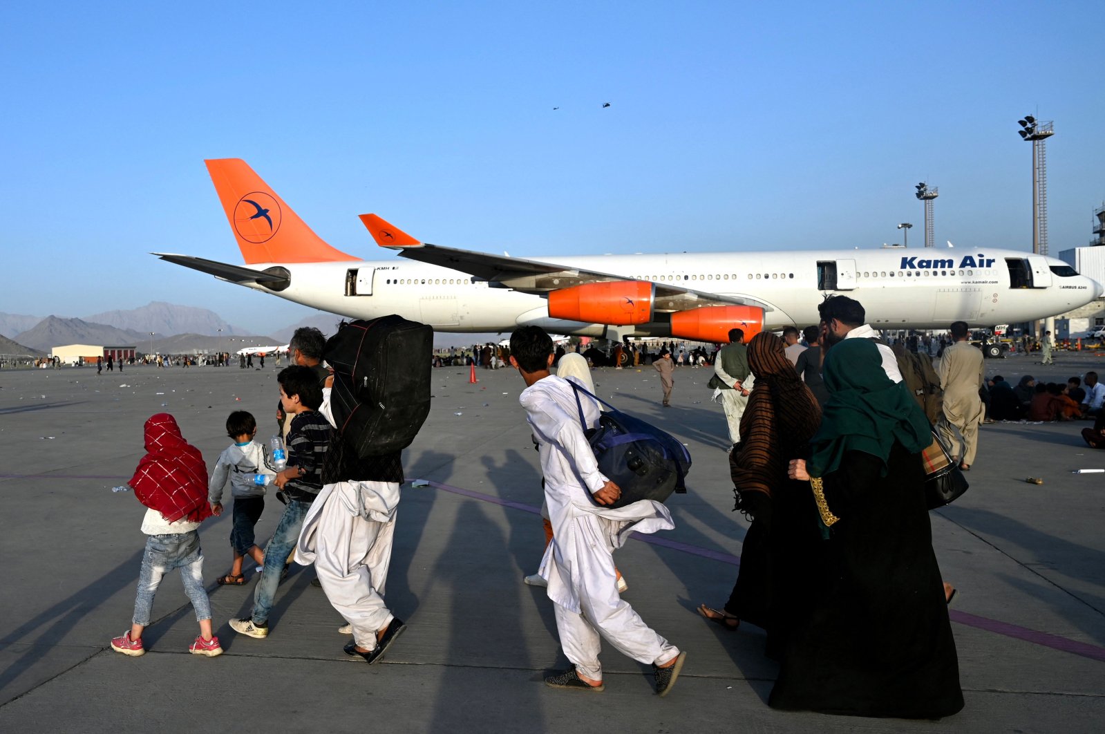 Afghan families walk by the aircraft at the Kabul airport in Kabul, Afghanistan, Aug.16, 2021. (AFP Photo)
