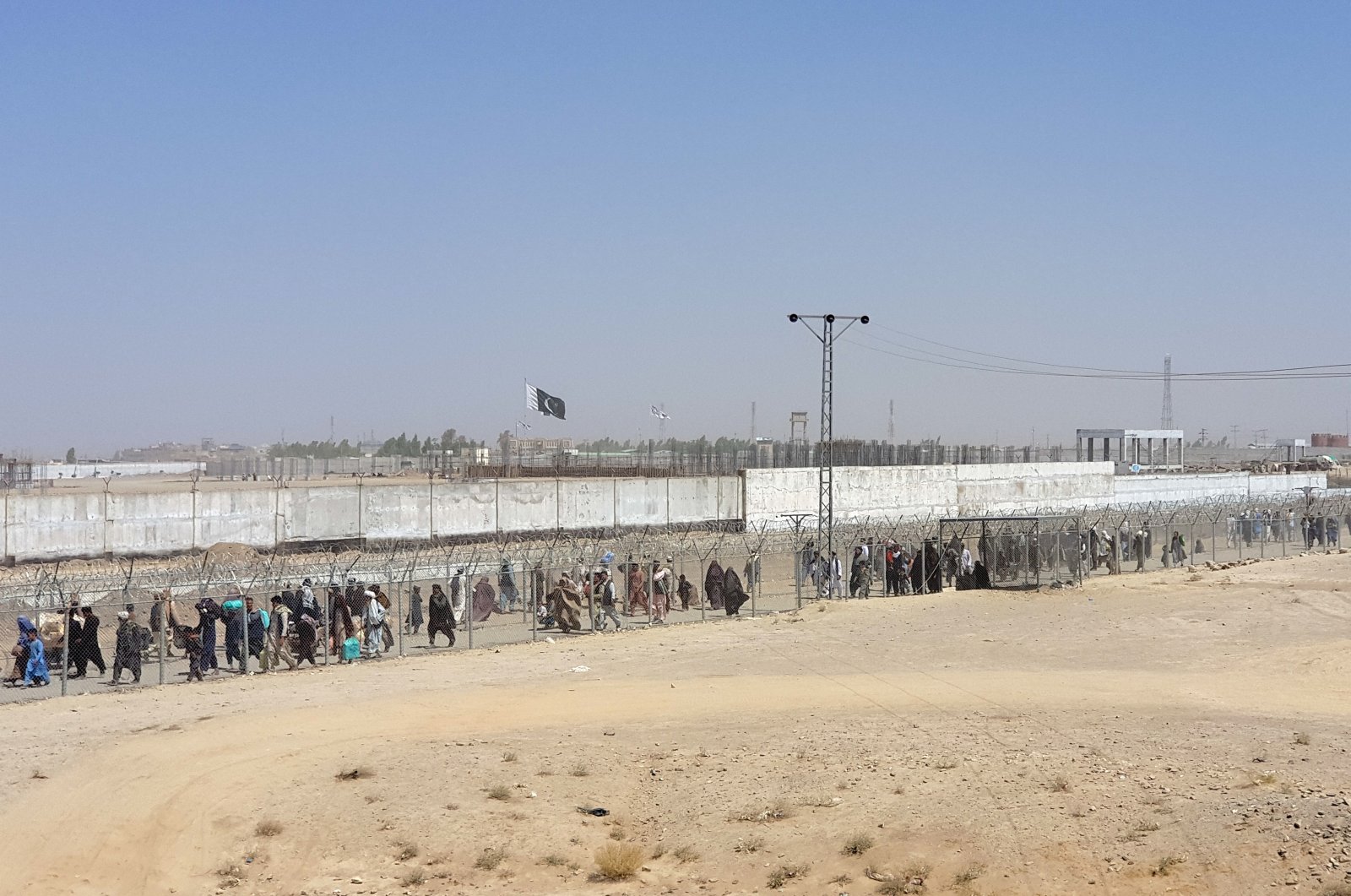 People arriving from Afghanistan cross the fence at the Friendship Gate crossing point, in the Pakistan-Afghanistan border town of Chaman, Pakistan, Aug. 18, 2021. (REUTERS)