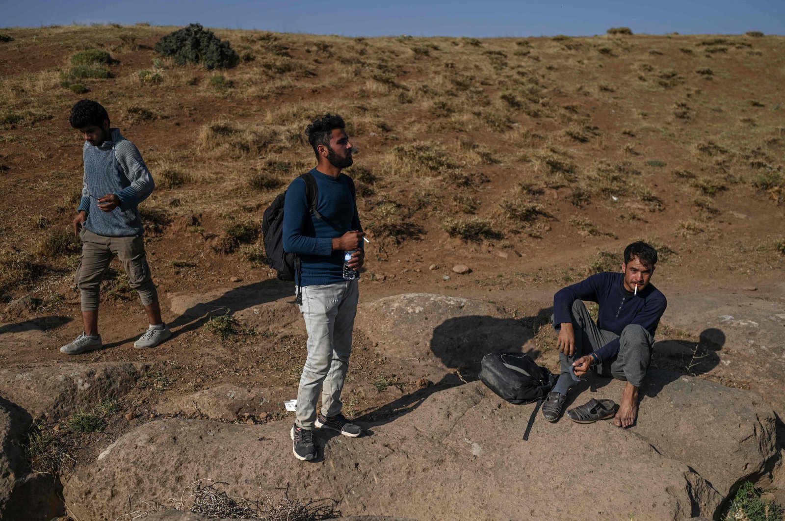 Afghan migrants rest while waiting for transport by smugglers after crossing the Iran-Turkish border on Aug. 15, 2021, in Tatvan, on the western shores of Lake Van, eastern Turkey. (Photo by Ozan KOSE / AFP)