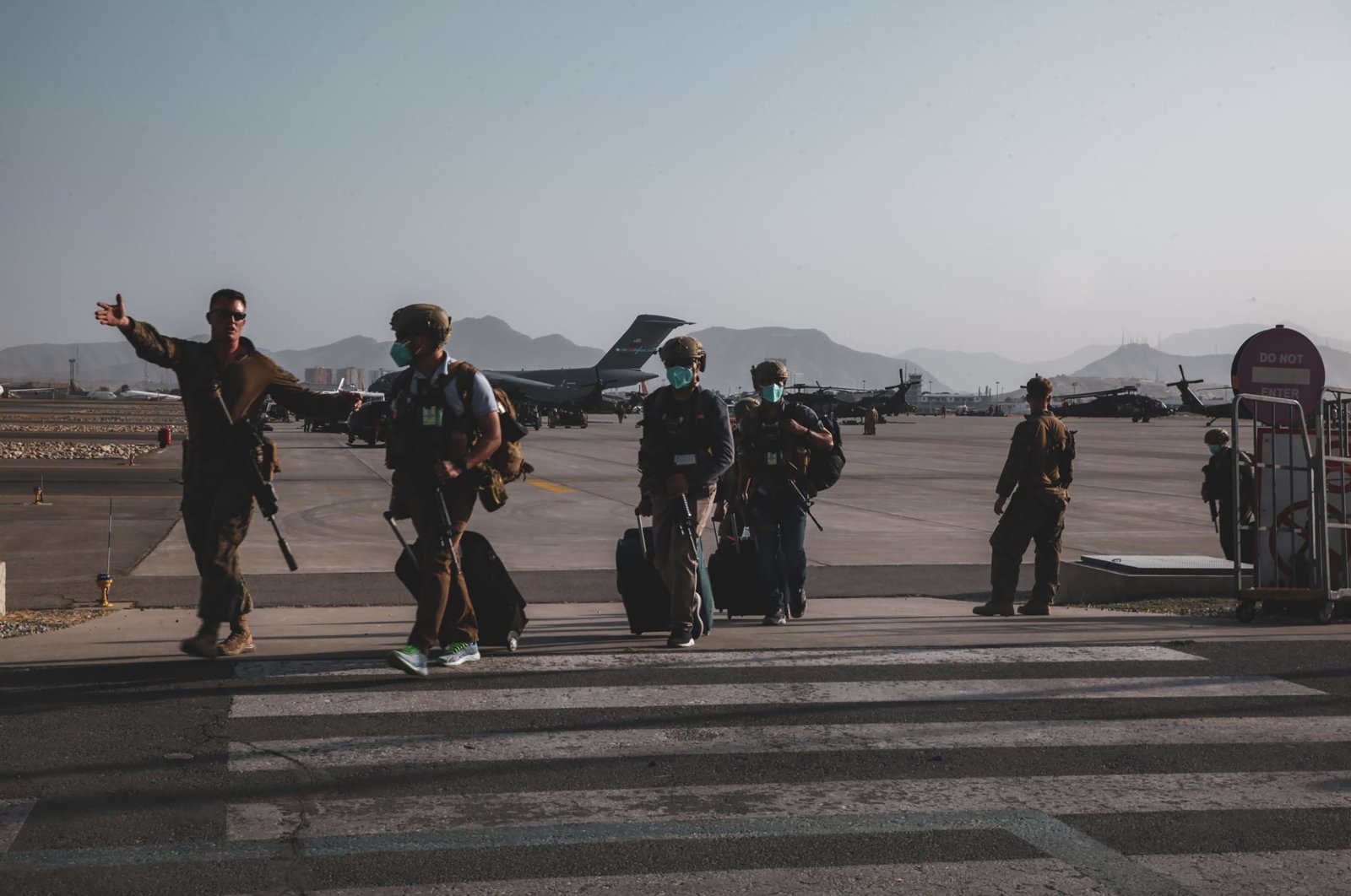 A U.S. Marine assigned to the 24th Marine Expeditionary Unit escorts U.S. State Department personnel to be processed for evacuation at Hamid Karzai International Airport, Kabul, Afghanistan, Aug. 15, 2021. (U.S. Marine Corps via AP)
