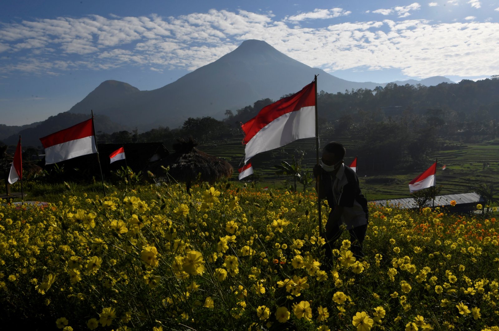 A man wearing a protective face mask holds an Indonesian flag to celebrate the country's 76th Independence Day at Refugia Park in Mojokerto, East Java province, Indonesia Aug. 17, 2021. (Reuters Photo)