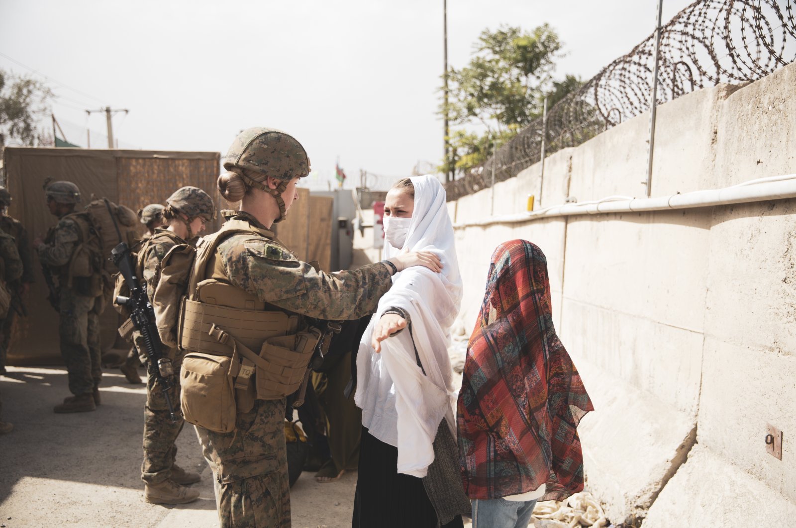 A Marine checks two civilians during processing through an Evacuee Control Checkpoint (ECC) during an evacuation at Hamid Karzai International Airport, Kabul, Afghanistan, Aug. 18, 2021. (U.S. Marine Corps photo via EPA)