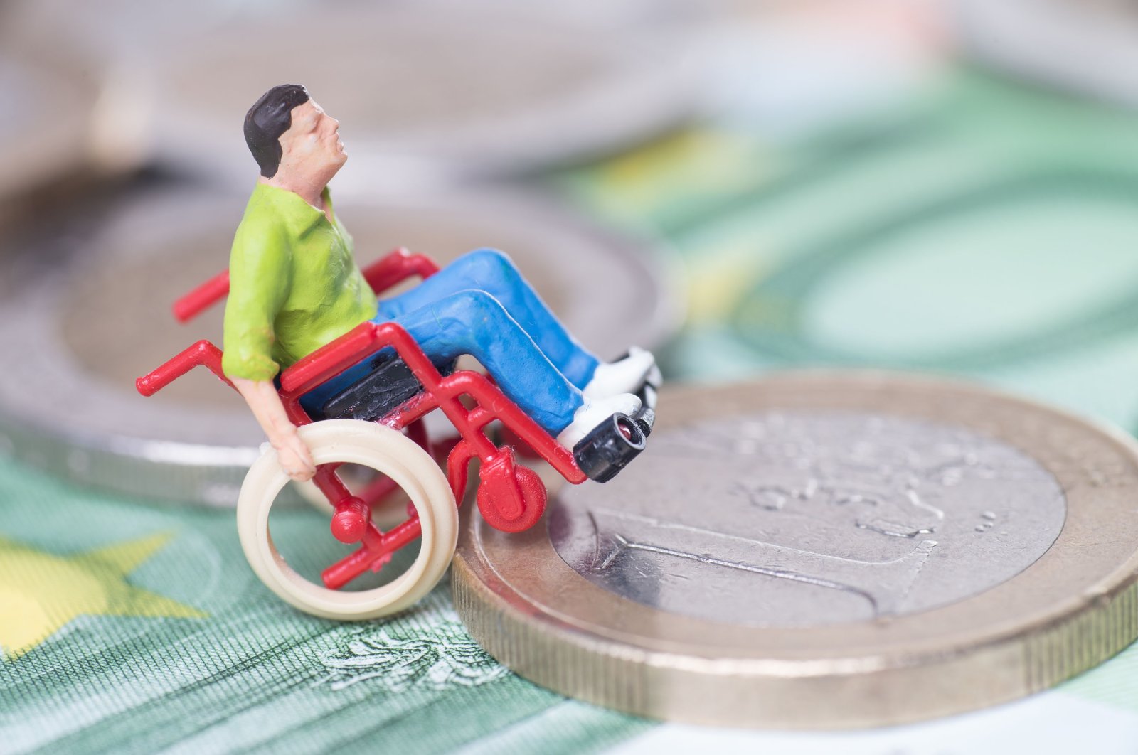 A figurine of a person in a wheelchair getting onto a coin. (Shutterstock)