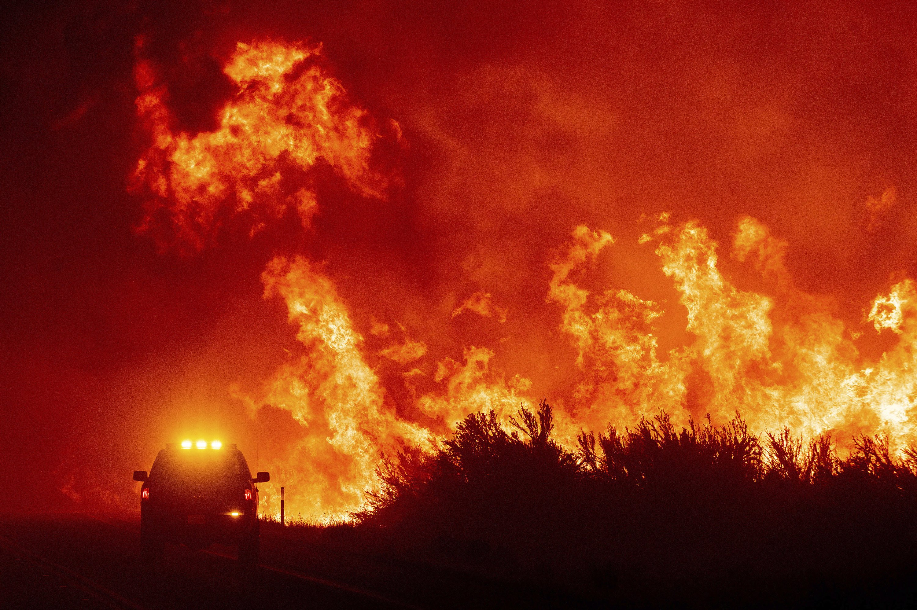 Flames leap above a fire vehicle as the Dixie Fire jumps Highway 395 south of Janesville in Lassen County, California, U.S., Aug. 16, 2021. (AP Photo)
