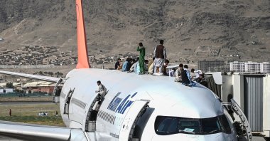 Afghan people climb atop a plane as they wait at Kabul Hamid Karzai International Airport in Kabul, Afghanistan, Aug.16, 2021. (AFP Photo)