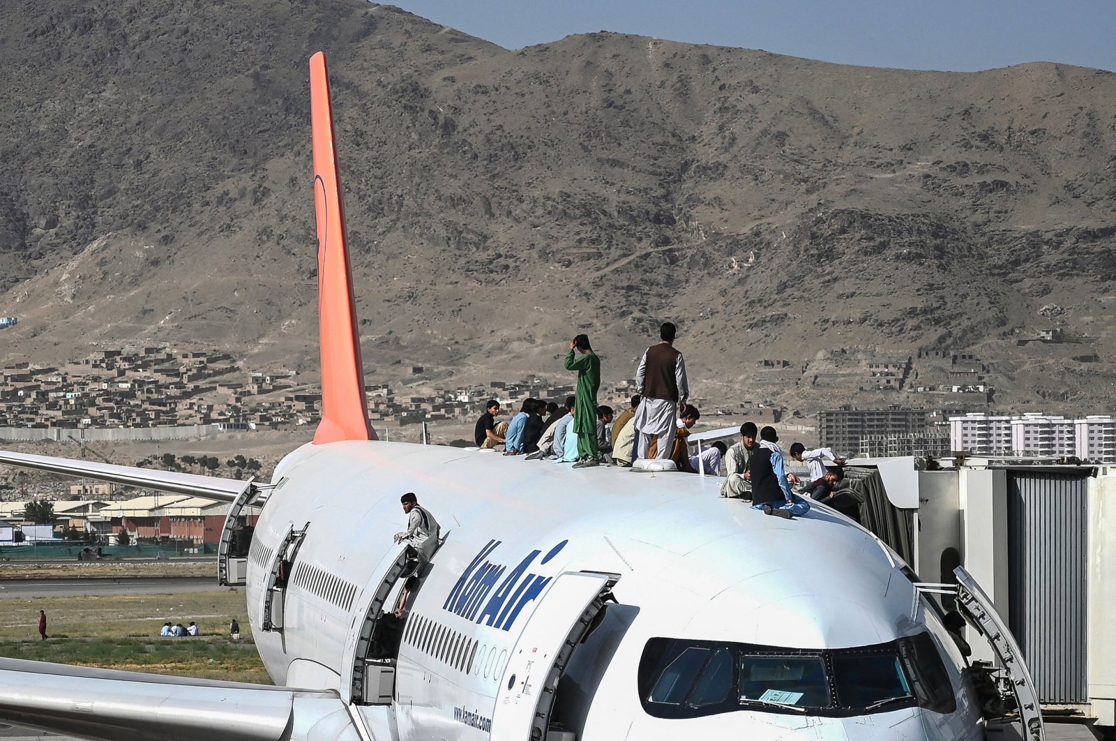 Afghan people climb atop a plane as they wait at Kabul Hamid Karzai International Airport in Kabul, Afghanistan, Aug.16, 2021. (AFP Photo)